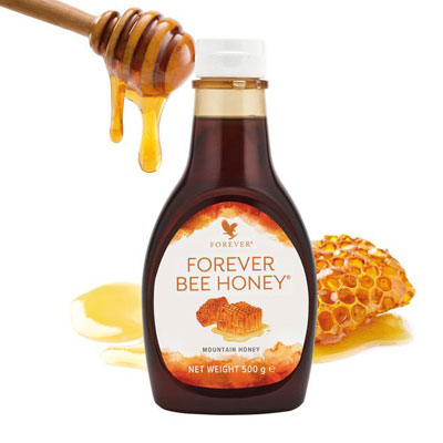 honigwabe und holzlöffel mit tropfendem honig, davor eine flasche forever honig